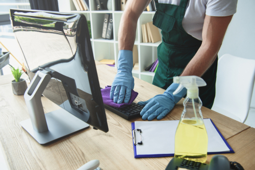 Cropped,shot,of,professional,cleaner,in,rubber,gloves,cleaning,computer