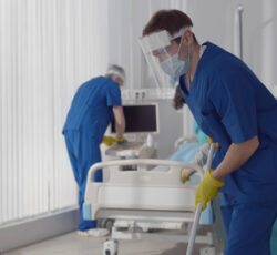 Janitors,in,scrubs,and,safety,mask,cleaning,hospital,room.,medical